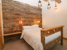 A bedroom with a bed and wooden wall at Cefnbron in Caernarfon