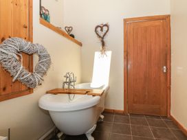 A bathroom with a bathtub and wooden door at Cefnbron in Caernarfon