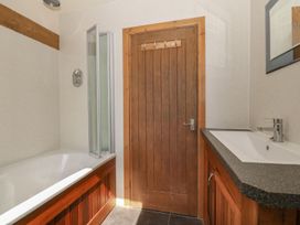 A bathroom with a bathtub, shower, door and sink at Cefnbron in Caernarfon
