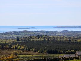 A view of the sea and islands with trees and fields at Cefnbron Caernarfon