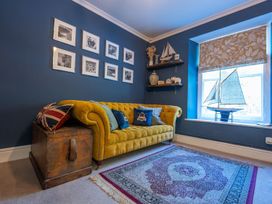 A living room with a yellow sofa and framed pictures at Gwynfryn House Llanbedr
