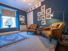 A living room with armchairs and a sailboat model at Gwynfryn House in Llanbedr
