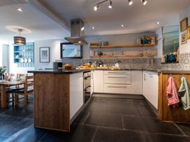 A kitchen with an island, shelves and dining table at Gwynfryn House in Llanbedr