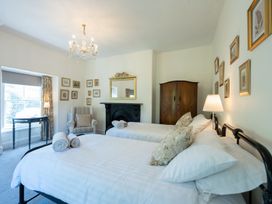 A bedroom with two beds and a chair at Gwynfryn House in Llanbedr
