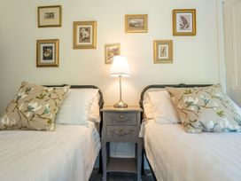 A bedroom with two beds and framed pictures on the wall at Gwynfryn House in Llanbedr