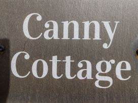 A wooden sign with the text Canny Cottage