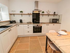 A kitchen with appliances and a dining table at Canny Cottage in Belford