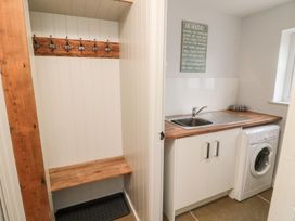 A utility room with a bench and washing machine at Canny Cottage in Belford