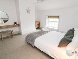 A bedroom with a bed and a mirror at Canny Cottage in Belford
