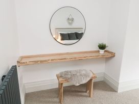 An entrance hall with a mirror and wooden shelf at Canny Cottage in Belford