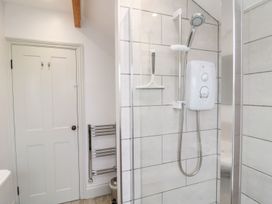 A shower area with a door and towel rail at Canny Cottage in Belford