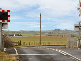 A railway crossing signal and an open road near fields at Canny Cottage in Belford