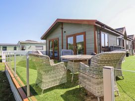An outdoor seating area with a table and chairs at Excalabur 10 in Morfa Bychan