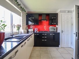 A kitchen with black units and red tiles at Excalabur 10 in Morfa Bychan