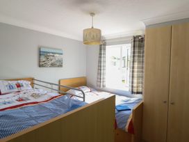 A bedroom with two beds and a wardrobe at Excalabur 10 in Morfa Bychan