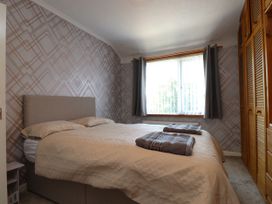 A bedroom with a bed, pillows, and a wardrobe at 31 Ffordd Y Maer, Pwllheli