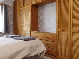 A bedroom with a bed, towels, wardrobe, and drawers at 31 Ffordd Y Maer in Pwllheli