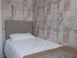 A bedroom with a bed and patterned wallpaper at 31 Ffordd Y Maer in Pwllheli