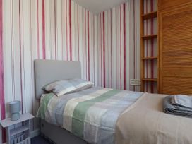 A bedroom with a bed, nightstand, and wardrobe at 31 Ffordd Y Maer in Pwllheli