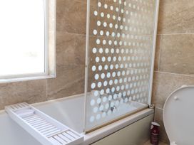 A bathroom with a bathtub and shower screen at 31 Ffordd Y Maer in Pwllheli