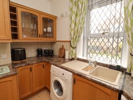 A kitchen with cabinets, sink, washing machine at 19 Dunstan View in Seahouses