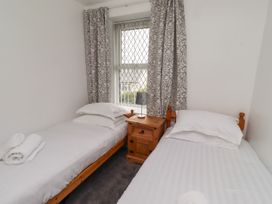 A bedroom with two single beds and a bedside table at 19 Dunstan View in Seahouses