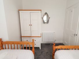 A bedroom with a wardrobe, two beds, and a mirror at 19 Dunstan View, Seahouses