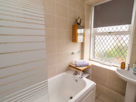 A bathroom with a bathtub, sink and window at 19 Dunstan View Seahouses