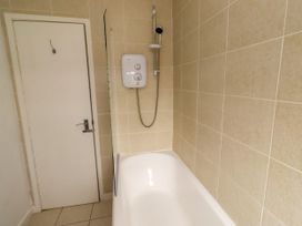 A bathroom with a bathtub and shower unit at 19 Dunstan View in Seahouses