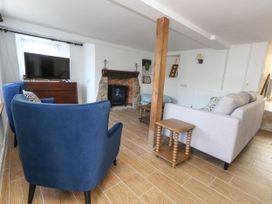 A living room with a television and a fireplace at Greenwich Cottage in Burton Bradstock