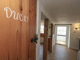 A hallway with a wooden door labeled Duck and a window at Greenwich Cottage in Burton Bradstock