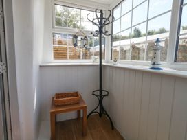 A conservatory with a coat rack and a table at Greenwich Cottage in Burton Bradstock