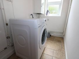 A laundry room with a washing machine and a window at Greenwich Cottage in Burton Bradstock