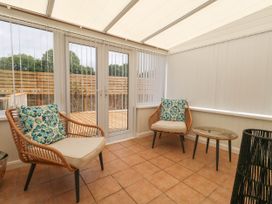 A conservatory with two chairs and a table at Greenwich Cottage in Burton Bradstock
