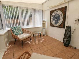 A conservatory with a clock and seating at Greenwich Cottage in Burton Bradstock