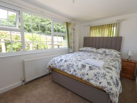 A bedroom with a bed and windows at Greenwich Cottage in Burton Bradstock