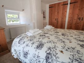A bedroom with a bed covered in floral bedding at Greenwich Cottage in Burton Bradstock