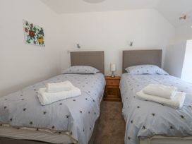 A bedroom with twin beds and a nightstand at Greenwich Cottage in Burton Bradstock