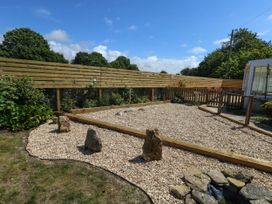 A garden with gravel, wooden fence, rocks and plants at Greenwich Cottage in Burton Bradstock