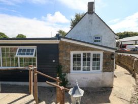The exterior of a house with a stone wall and windows at Greenwich Cottage in Burton Bradstock