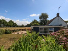 A garden with a house and basketball court at Greenwich Cottage in Burton Bradstock