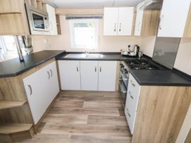 A kitchen with a sink, stove, and microwave at Number 19 Ferryside