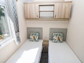 A bedroom with two single beds and a shelf at Number 19 in Ferryside