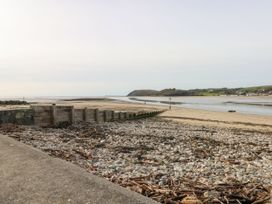 A beach with water and a wooden structure at Number 19 in Ferryside