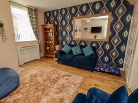 A living room with a sofa, bookshelf and mirror at The Old Bank House Red Row near Amble