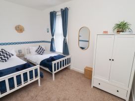 A bedroom with two beds and a wardrobe at The Old Bank House Red Row near Amble