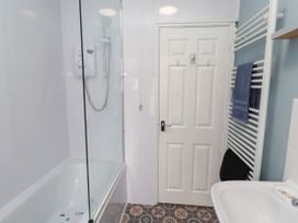 A bathroom with a bathtub shower and sink at The Old Bank House Red Row near Amble