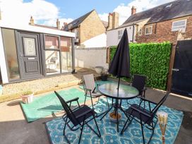 An outdoor seating area with a table and chairs at The Old Bank House in Red Row near Amble