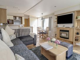 A living room with a sofa and dining area at Plot 13A