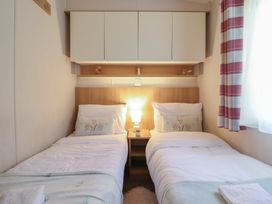 A bedroom with two beds and a lamp at Plot 13A